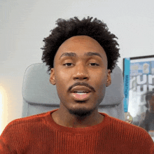 a man in an orange sweater is sitting in a chair