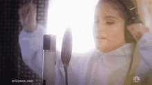 a woman wearing headphones is singing into a microphone on nbc 's songland show