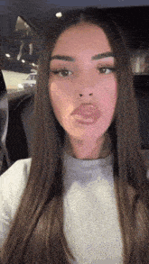 a woman with long hair is sitting in the back seat of a car .