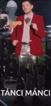 a man in a red jacket and silver pants is standing in front of a sign that says tanti manci