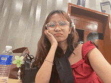 a bottle of aquafina water sits on a table next to a woman wearing glasses