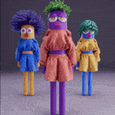 three colorful dolls are standing next to each other and one has a green hairdo