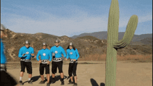 a group of people standing in front of a large cactus