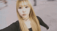 a woman with long blonde hair is taking a selfie with her hands outstretched .