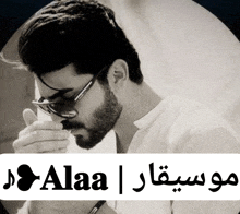 a man with a beard wearing sunglasses and a white shirt is smoking a cigarette in a black and white photo .