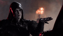 a man wearing a black hooded jacket is holding something in his hand