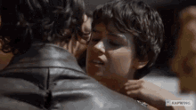 a man and a woman are kissing with their eyes closed . the woman is wearing a leather jacket .