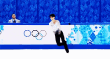 a man is skating in front of a sign that says olympics