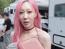 a woman with pink hair and a red choker is holding a red container