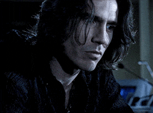 a close up of a man 's face with long dark hair