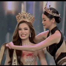 a woman is putting a crown on another woman 's head at a pageant .