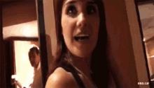 a woman is standing in a hallway with a man behind her and the words rbd.gif below her
