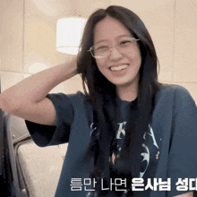 a woman wearing glasses and a t-shirt with the letter k on it smiles