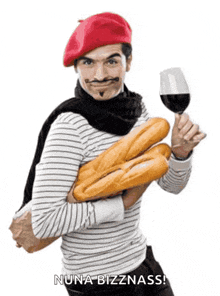 a man wearing a red beret is holding a glass of wine and bread