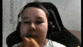 a young boy wearing headphones is biting a piece of bread