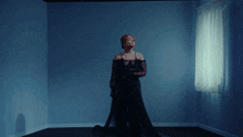 a woman in a long black dress is standing in a dark room