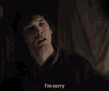 a man is saying i 'm sorry in a dark room