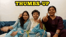 three women are sitting on a couch and giving a thumbs up sign