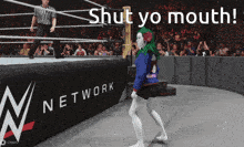 a woman with green hair is walking in front of a wrestling ring that says network