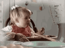 a little girl is sitting at a table eating food from a bowl .