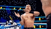 a shirtless wrestler is standing in a wrestling ring with his hands outstretched .