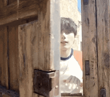 a man is looking through a wooden door while holding a piece of paper