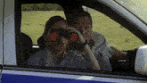 a man and woman are looking through binoculars in a car