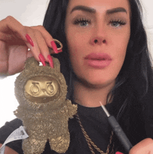 a woman with long red nails is holding a gold keychain with the number 50 on it
