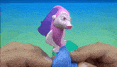 a person is holding a pink and purple toy dolphin in their hands .