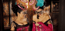 two women wearing masks are standing next to each other in a room