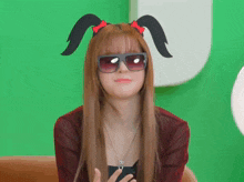 a woman wearing sunglasses and bunny ears looks at the camera