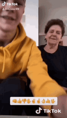 a man in a yellow hoodie sits next to an older woman in a black shirt and a tiktok sticker