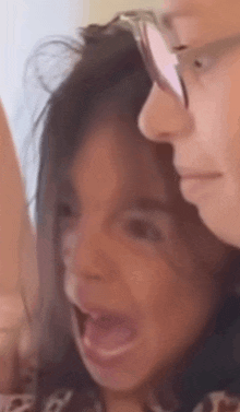a close up of a woman 's face with her mouth open and a man behind her .