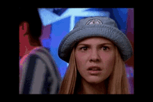 a woman wearing a blue hat with a logo on it looks surprised and shocked