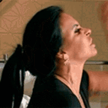 a woman with long black hair is wearing a ponytail and earrings .