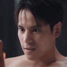 a shirtless man is looking at his face in the mirror .