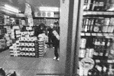 a black and white photo of a grocery store with a person standing in the doorway .
