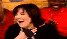 a woman is laughing while holding a microphone in front of a man .