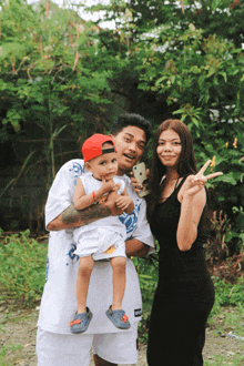 a man in a white shirt with the word supreme on it is holding a baby