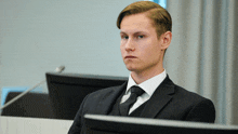 a man in a suit and tie is sitting in front of a computer monitor