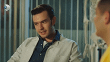 a man in a lab coat talks to another man in a yellow shirt