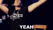 a man wearing a shirt that says yeah is making a hand gesture