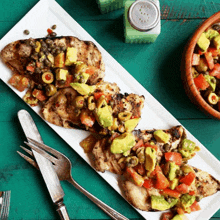a white plate topped with chicken avocado and olives