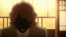 a man in a suit is standing in front of a window with his face obscured by a shadow .
