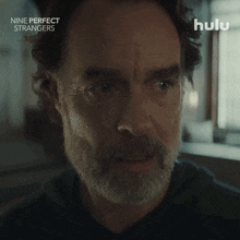 a close up of a man 's face with the words " nine perfect strangers " behind him