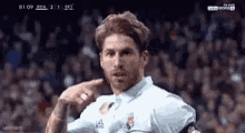 a man in a white shirt is standing in front of a crowd of people on a soccer field .