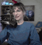 a woman wearing glasses is smiling in front of a microphone .