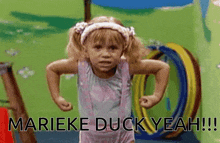 a little girl is flexing her muscles and says marieke duck yeah !!