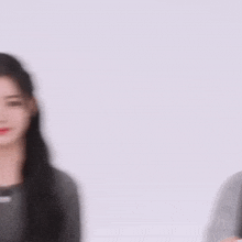 a girl with long black hair is wearing a gray shirt and earrings
