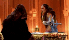 a woman in a costume is holding a sword and talking to another woman .